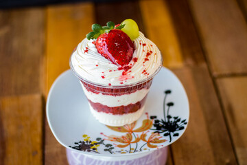 Mousse and pot cake, chocolate, strawberry and other creams, sugared strawberry, with chocolate bonbon, spoon, fabric, rustic wood