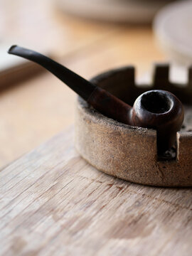 wooden pipe sitting in an ashtray on a wooden tabletop, Canada