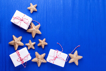 Frame  from wrapped boxes with presents  and golden decorative stars on blue paper  textured  background. Place for text. Flat lay. Holiday layout.
