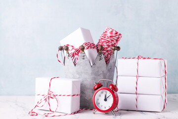 Postcard with red clock and  wrapped boxes with presents in decoative zink  crown against  blue textured  wall. Scandinavian style. Place for text.