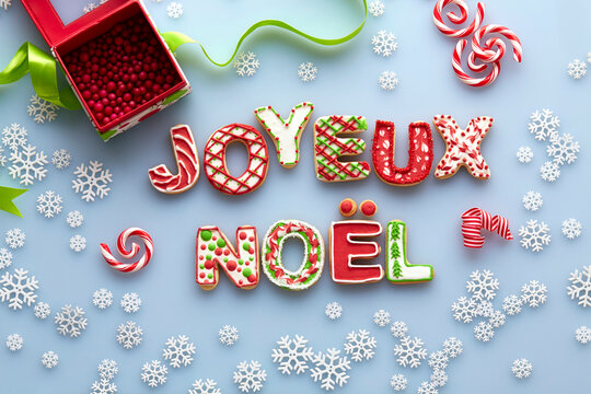 Overhead View of Christmas Sugar Cookies spelling JOYEUX NOEL on Blue Background with Snowflakes