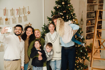 Cheerful family taking selfie while standing together near Christmas tree