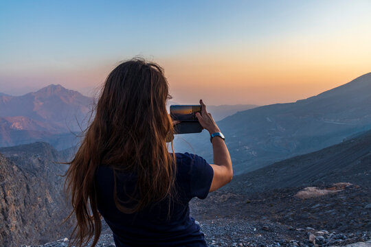 Shot of a young woman taking a picture in the mountains. Outdoors