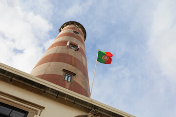 Aveiro Lighthouse, Farol da Praia da Barra, Ilhavo, Portugal - building and landmark with Portuguse waving flag. Bottom view and low angle.