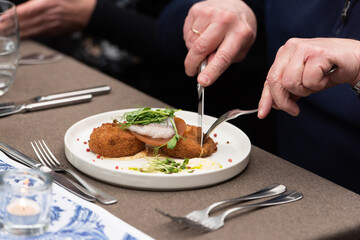 man eating herring with potato Kroket croquette Dutchs favourite snack deep-fried ragout filled snack in a restaurant