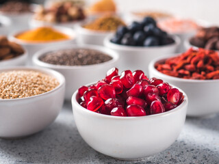 pomegranate or grain of garnet in small white bowl and other superfoods