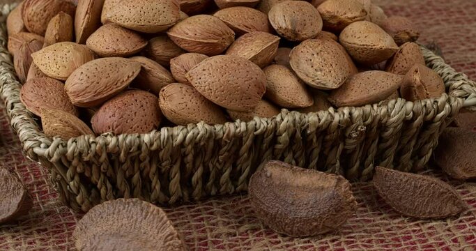 Unshelled almonds in braided basket and unshelled Brazil nuts. Table spin. 