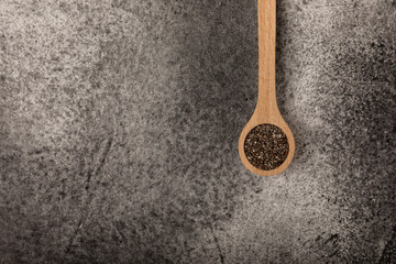 Chia seeds in a wooden spoon on a black marble background. Superfood. Healthy food.
