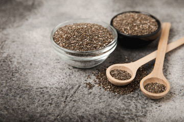 Chia seeds in bowls and wooden spoons on a black marble background. Superfood. Healthy food. Diet. Antioxidant. Place for text. Place to copy.