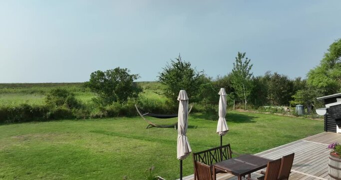 Luftaufnahme von einem Ferienhaus in D&auml;nemark direkt an der Ostsee - Reveal vom Meer hinter einem gr&uuml;nen Deich 