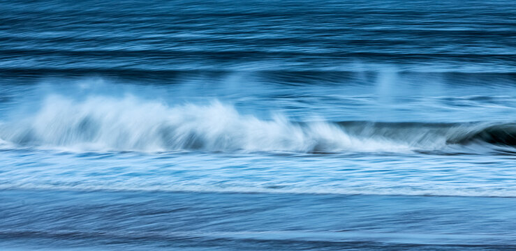 Blurred motion of waves crashing on the shoreline; England, United Kingdom