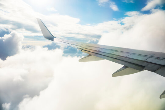 Airplane wing in sunlit clouds during travel down the coastline of Australia; Cairns, Australia