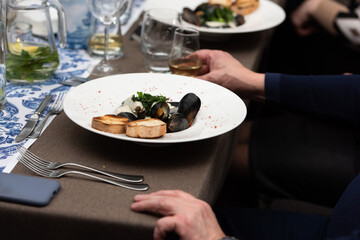man going to eat mussels in white wine sauce and white bread toasts in a restaurant