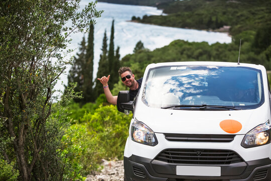 Man Hanging Out Car Window And Driving Camper Van To Find A Secluded Beach Along The Croatia Coastline; Zaton Doli, Dubrovnik-Neretva County (Dubrovacko-neretvanska Zupanija), Croatia