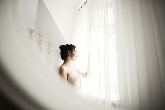 Beautiful bride wearing fashion wedding dress with feathers with luxury delight make-up and hairstyle, studio indoor photo shoot