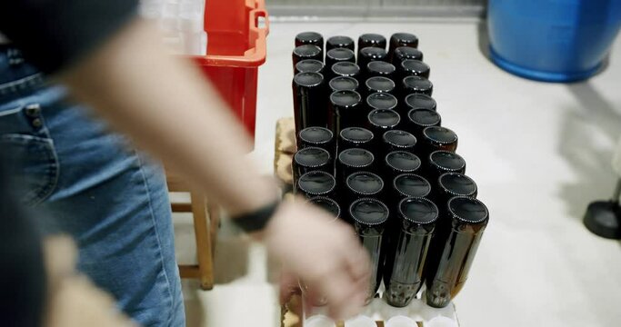 Close-up of hands collecting glass bottles and placing them on the automatic brewery line. Brewery factory concept. Modern technology in a factory. Factory, beer concept.
