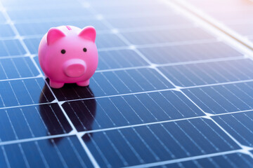 Energy saving concept with solar panels and a piggy bank