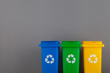 Plastic yellow, green and blue trash can on a gray background