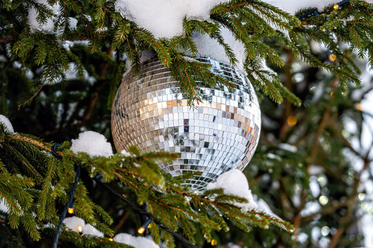 Christmas disco ball decoration on a snowy Christmas tree branch. Selective focus