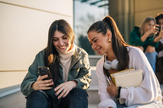 Two joyful college students are looking at the phone