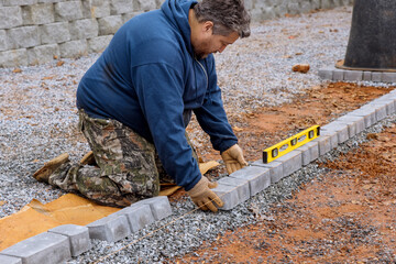 Construction worker installing arranging precast concrete pavers stone for road sidewalk