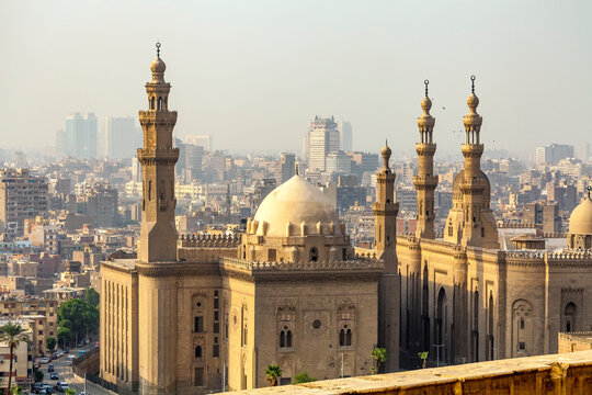 View overlooking the Mosque of Sultan Hassan at the Citadel and the and the Al-Rifai Mosque at Midan al-Qal'a, with the hazy sky over the city skyline in the background; Cairo, Egypt