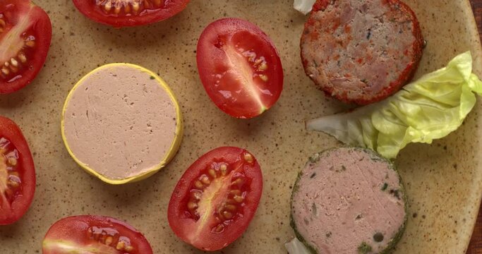 Selection of pates decorated with tomatoes and lettuce leaves on a plate. Top view, table spin.