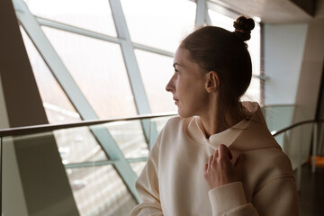 Young woman indoors looking at the panoramic view from the window