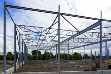 Fototapeta premium Assembled steel framework of new modern industrial building with foundation concrete panel border