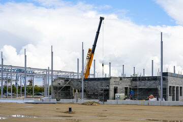 Fototapeta na wymiar Telescopic boom crane on construction site of a new steel framework warehouse building