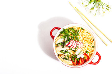 Asian noodles with chicken, vegetables, and herbs are isolated on a white background