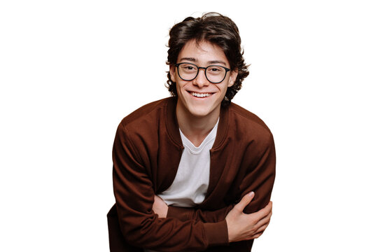 Cheerful caucasian guy in glasses, brown sweatshirt and white t-shirt posing at studio against transparent backdrop toothy smiles. Handsome male teenager indoors. Youth, happiness. Handsome people.