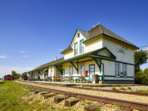 A quaint train station and decorated platform with tracks running by; Camrose, Alberta, Canada