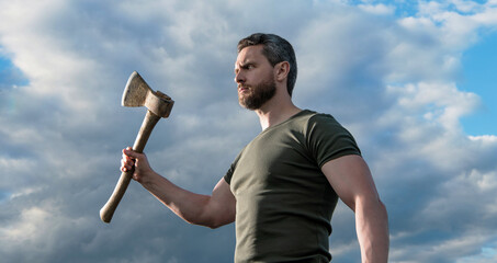 confident guy with axe. caucasian guy hold ax. brutal guy on sky background