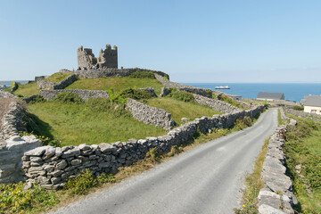 O'Brien's Castle on Inis Oirr (Inisheer), one of the Aran Islands with the expedition ship, the National Geographic Explorer, in the distance in Galway Bay; County Galway, Ireland