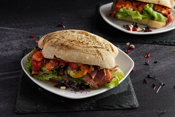 Pastrami sandwich served on a white plate on dark background.