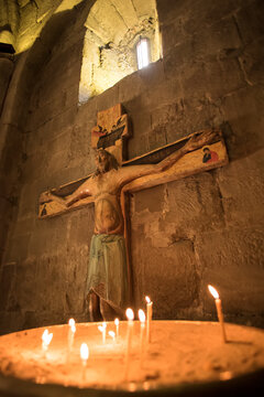 Candles burn in front of a wooden depiction of Jesus Christ on the cross; Mtskheta, Georgia