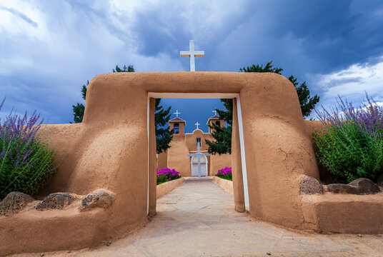 Looking through the adobe gates to the courtyard entrance and facade of the historic San Francisco de Asis Church on the main plaza of Ranchos de Taos; Taos, New Mexico, United States of America