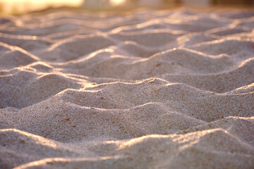 Close up of clean yellow sand surface covering seaside beach illuminated with evening light. Travel and vacations concept
