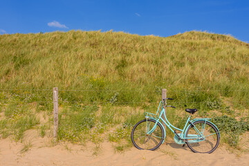 Fototapeta premium bicycle on the beach. A blue bicycle against the fence in the dunes