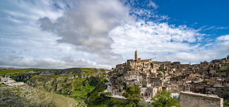 Cityscape panorama of the mountaintop town of Sassi di Matera and its ancient cave dwellings with the bell tower of the Matera Cathedral overlooking the city; Matera, Basilicata, Italy