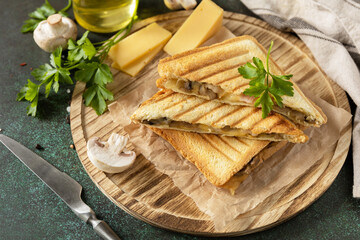 Delicious sandwich with grilled cheese, bacon and mushroom. Homemade breakfast on a dark stone tabletop.