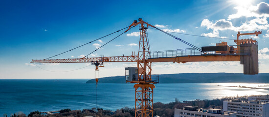 Panoramic view from a drone to construction tower crane against a blue sky