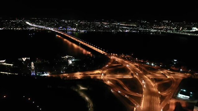 Paton Bridge in Kyiv at night, Ukraine. Aerial view. Car traffic on bridge. Circular movement of cars. Night. 