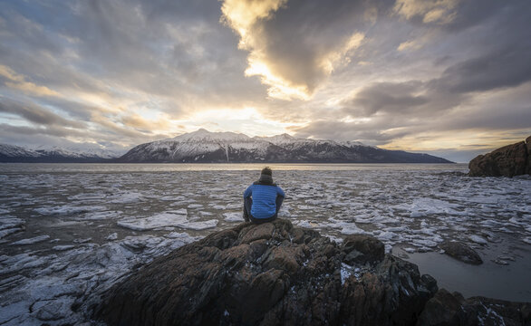 Man sitting on rocks at the outpost of Beluga Point at Turnagain Arm, Alaska, USA