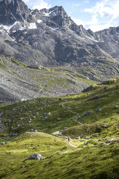 Lone hiker and her dog on the Reed Lakes Trail are dwarfed by the impressive scenery; Palmer, Alaska, United States of America