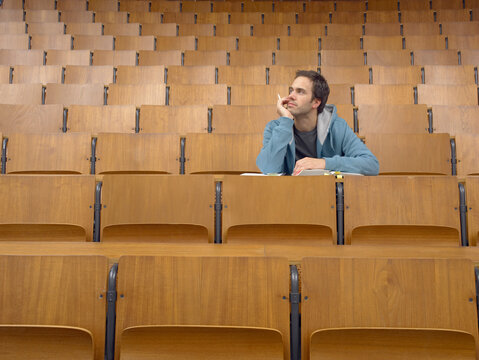 Student waiting in an empty lecture hall; Germany