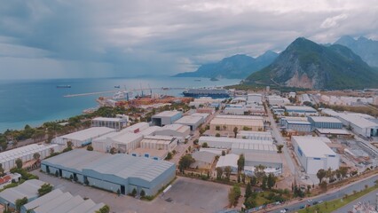 Aerial drone view of storage facilities of the cargo port on the seashore. Mountains in the background