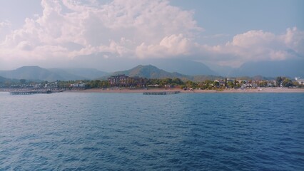 Aerial view flight over the blue sea at sunset. Beautiful clouds. Mountains in the background. Seascape. Photography