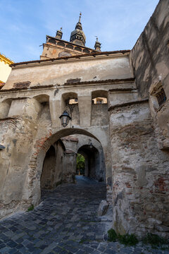 Gateway arch and cobblestone street below the clock tower to the Citadel and Old Town of Sighisoara, place of birth of Vlad Tepes (Dracula); Sighisoara, Transylvania, Romania